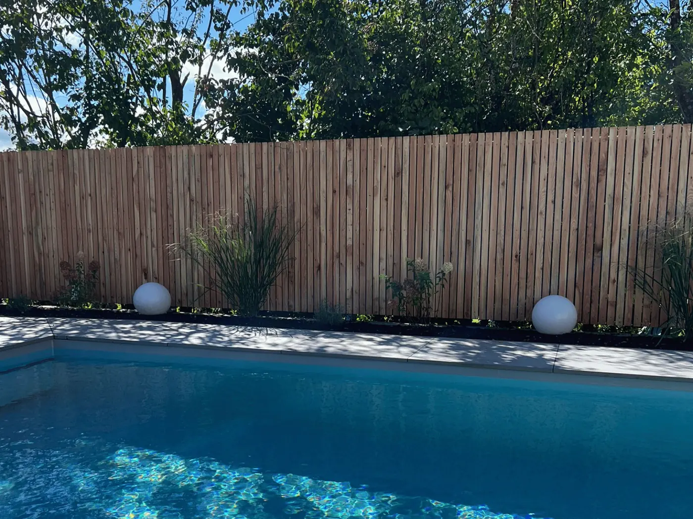 Sichtschutzzaun aus Holz an einem Pool im Garten