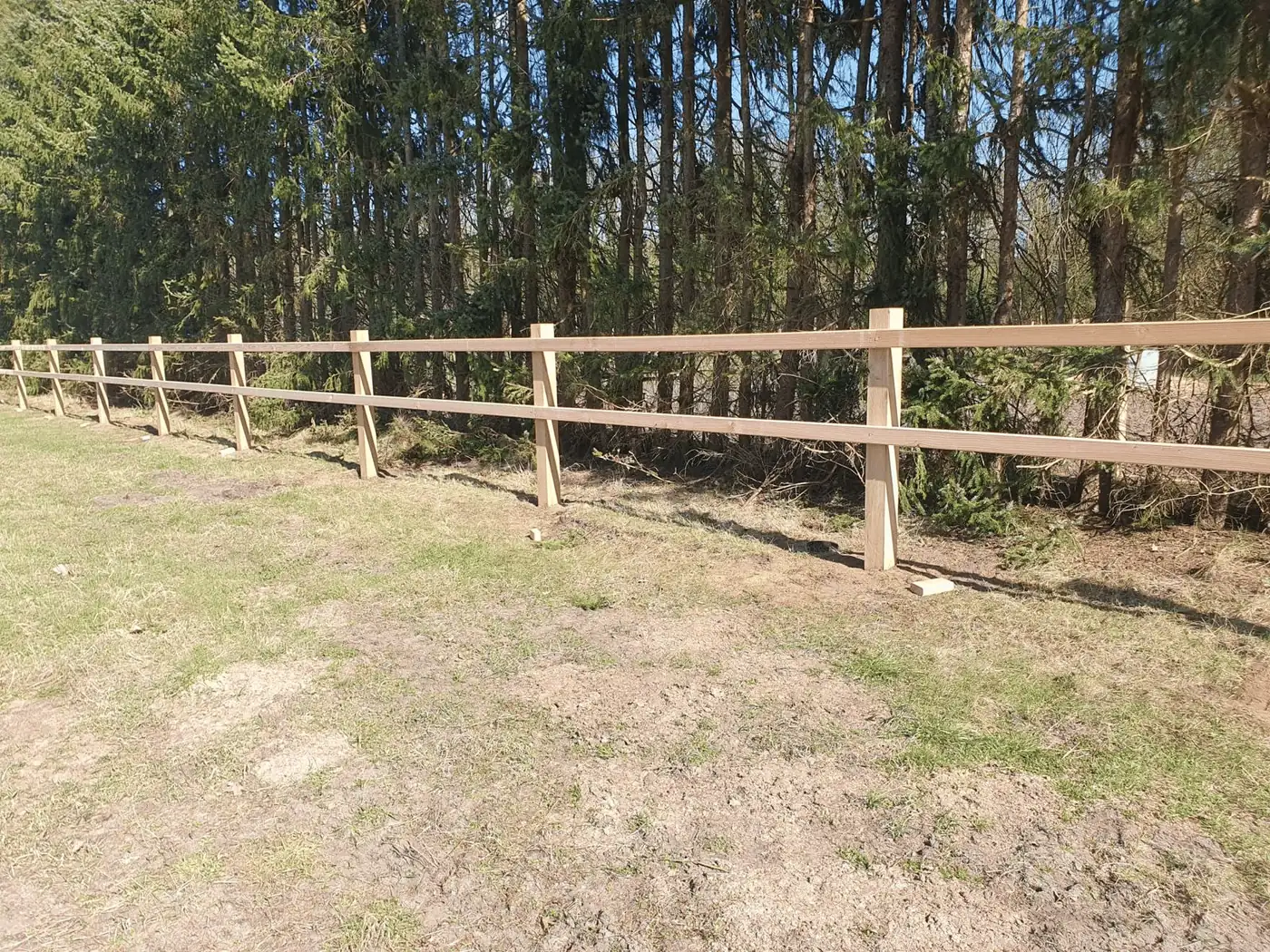 Pferdezaun aus Holz mit zwei Riegeln am Waldrand