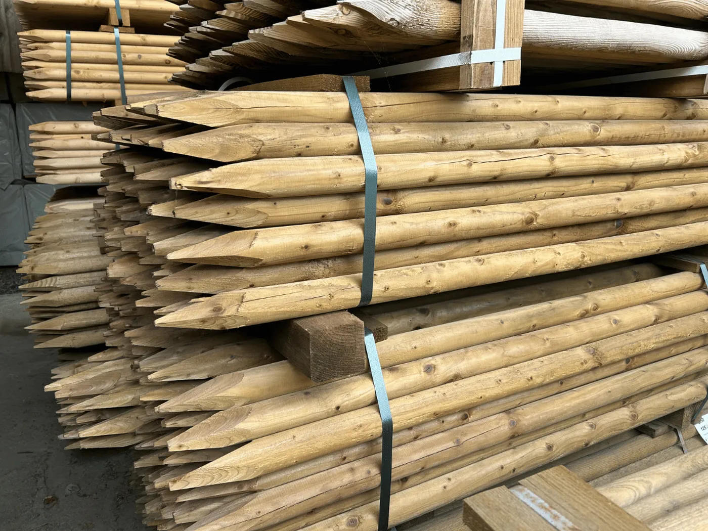 Nadelholzpfähle gespitzt, gebündelt auf Paletten im Lager